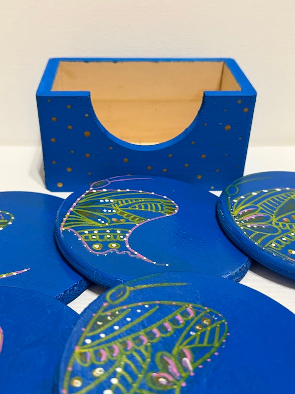 Blue coasters with green and pink designs with a holder
