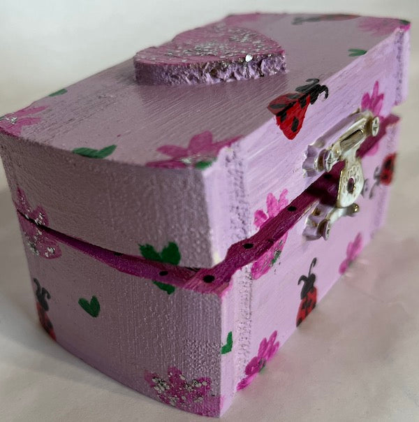 Side view of a small hand painted box with green hearts and lady bug