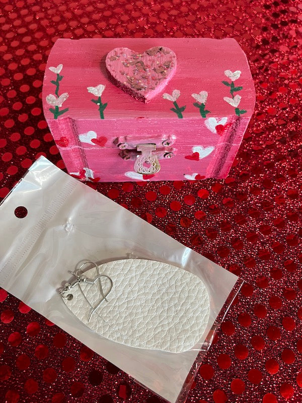 A small wooden box with white leather earrings