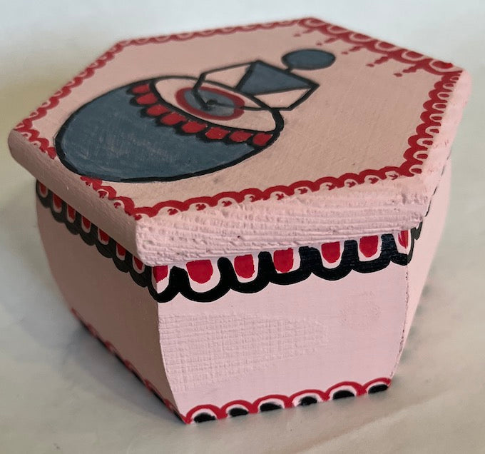 A pink hexagon shaped hand painted warli gift box