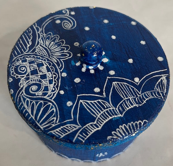 A blue and white hand painted round wooden box with lid