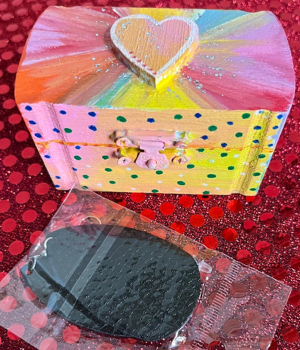 A colorful hand painted gift box with a black leather earring