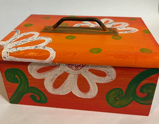 An orange hand painted wooden box with a removable lid